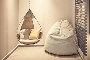A room with a hanging chair, a bean bag, and a wall-mounted light fixture.