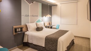Et moderne hotelværelse med seng, sengebord og skrivebord med stol.