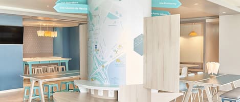 A modern interior with a central map display, seating areas, and a television.