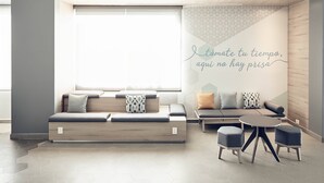 Et moderne opholdsområde med sofa, skærmstole og en væg med geometrisk mønster og et motiverende citat.
