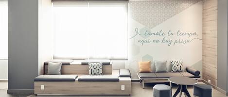 A modern lounge area with a sofa, chairs, and a wall with a geometric pattern and a motivational quote.