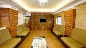 A lobby with a wooden wall, a flat-screen TV, and two sofas. - Treebo The Qasr (Kanayannur)