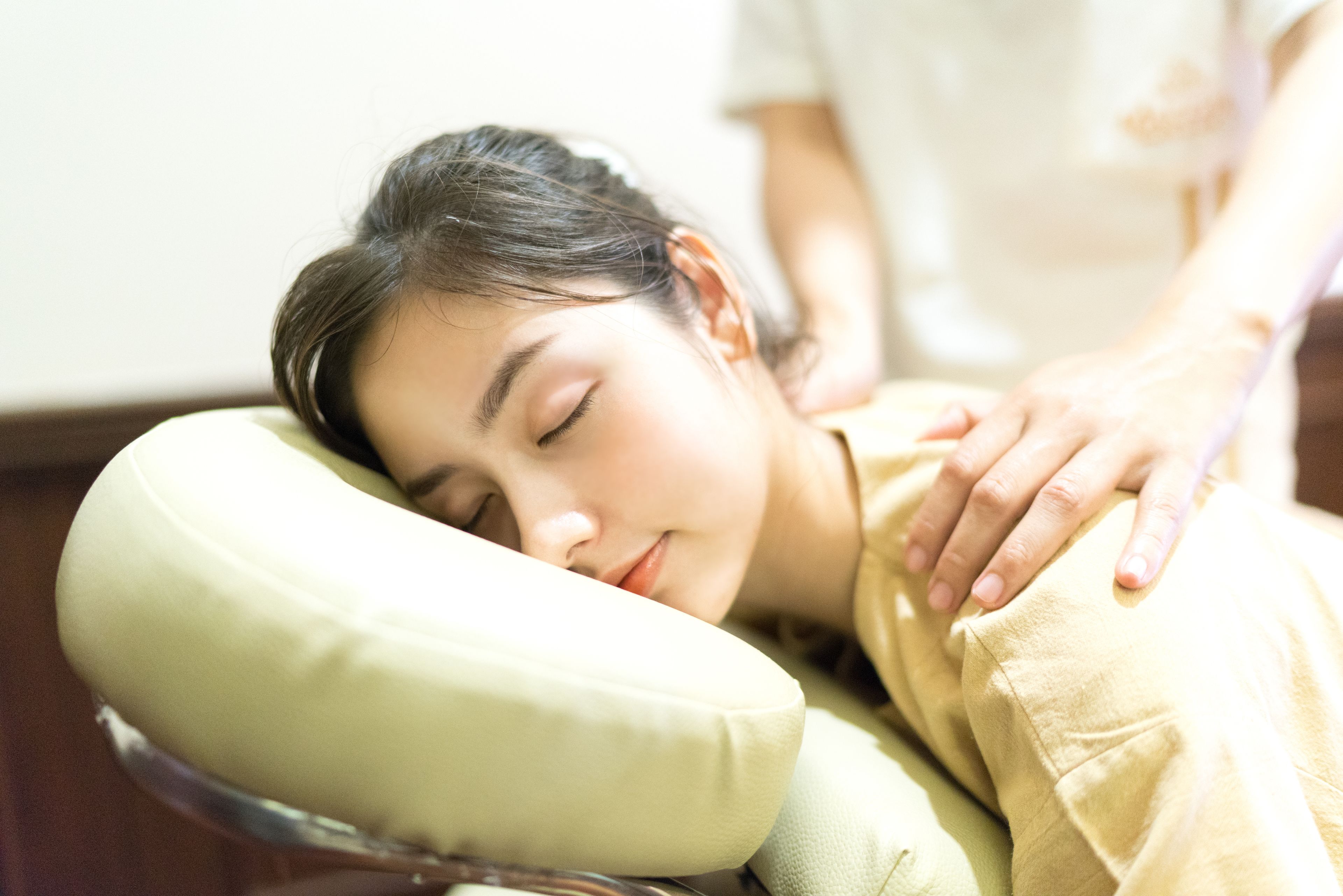 A person receiving a massage with a focus on the backrest of the massage chair.