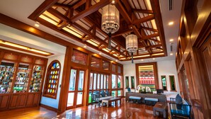 A spacious lobby with wooden beams, a seating area, and a reception desk. - Phra Singh Village (Chiang Mai)