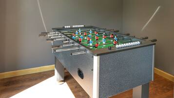 A foosball table in a room with a dark wall and a hanging light fixture.