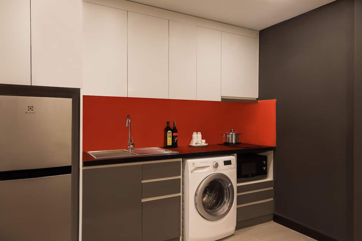 A compact kitchen with a washing machine, a microwave, and a sink.