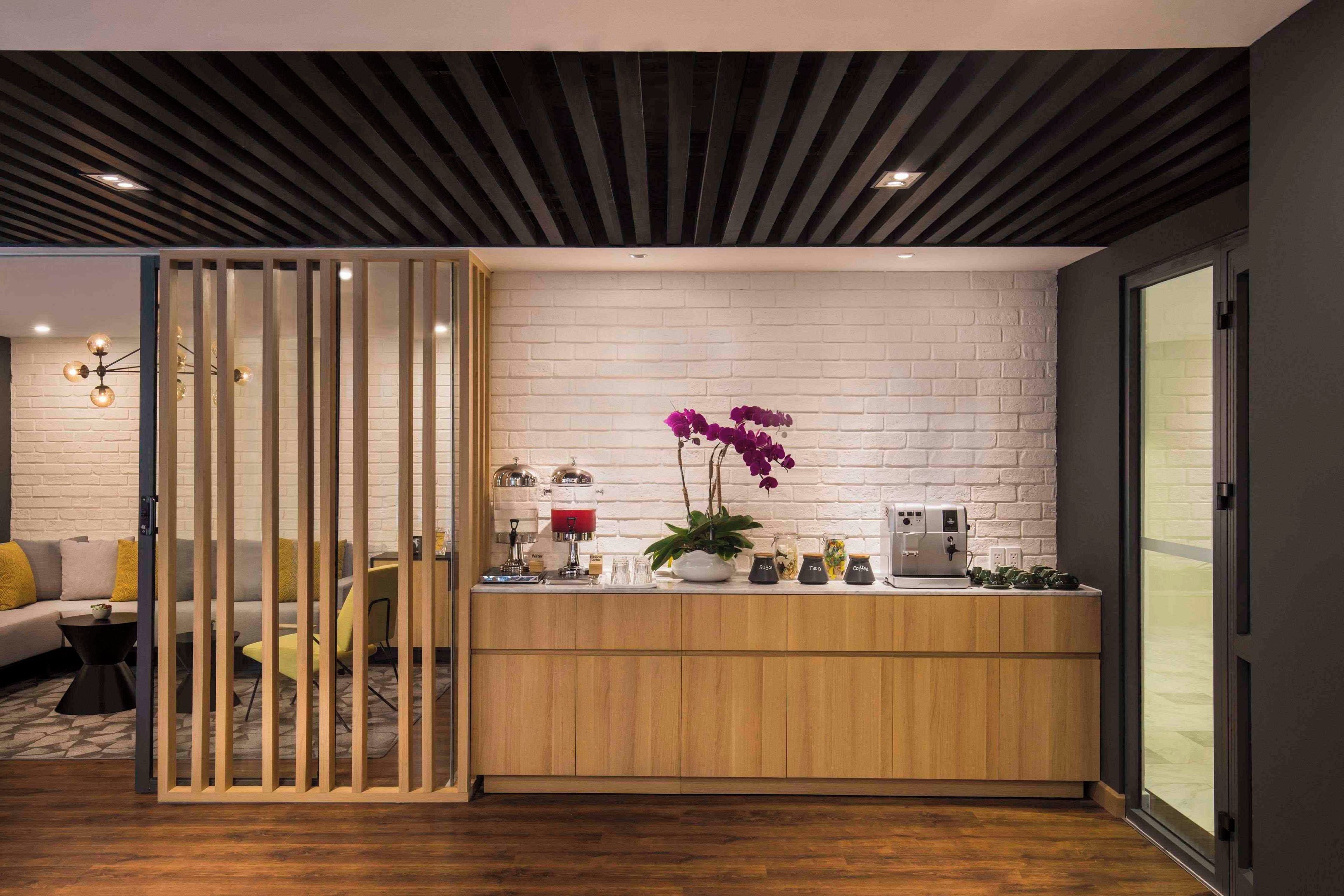 A modern reception area with a wooden counter, a coffee machine, and a water dispenser.