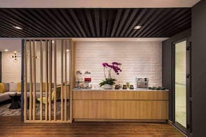 Una zona de recepción moderna con mostrador de madera, máquina de café y dispensador de agua.