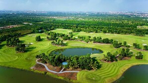 Un campo de golf con varios hoyos, cuerpos de agua y abundante vegetación.