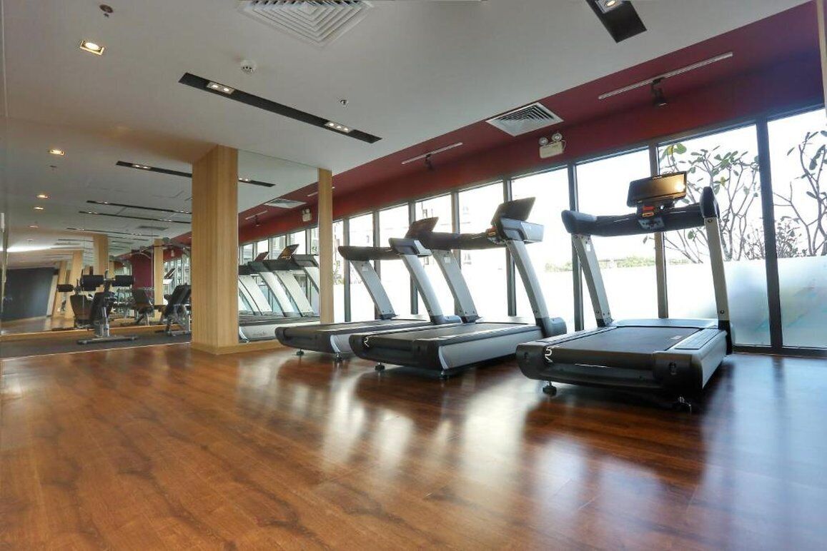 Ett gym med löpband, trägolv och stora fönster.
