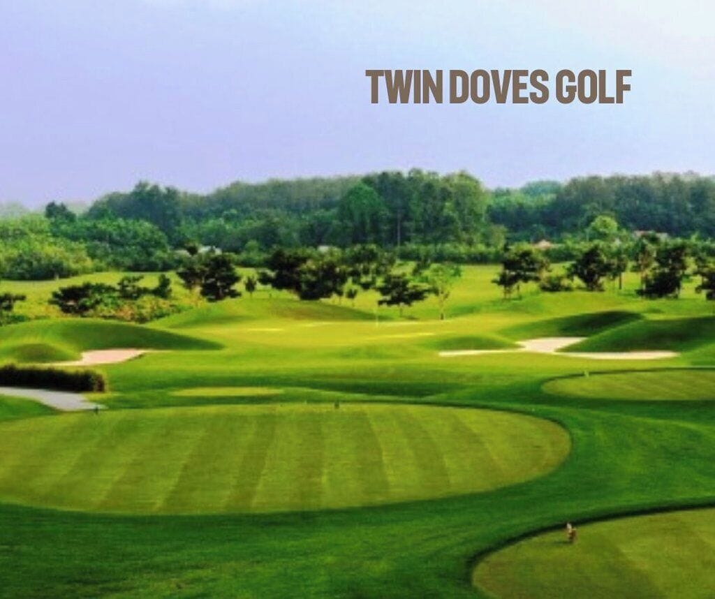 A golf course with well-manicured greens, sand bunkers, and a clear sky.