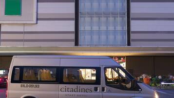 A Citadines van parked in front of a building with large windows and a green sign on the wall.