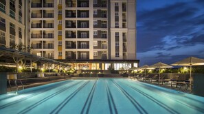 A hotel with a swimming pool, outdoor seating, and a large building with multiple balconies. - Citadines Central Binh Duong (Ho Chi Minh City)