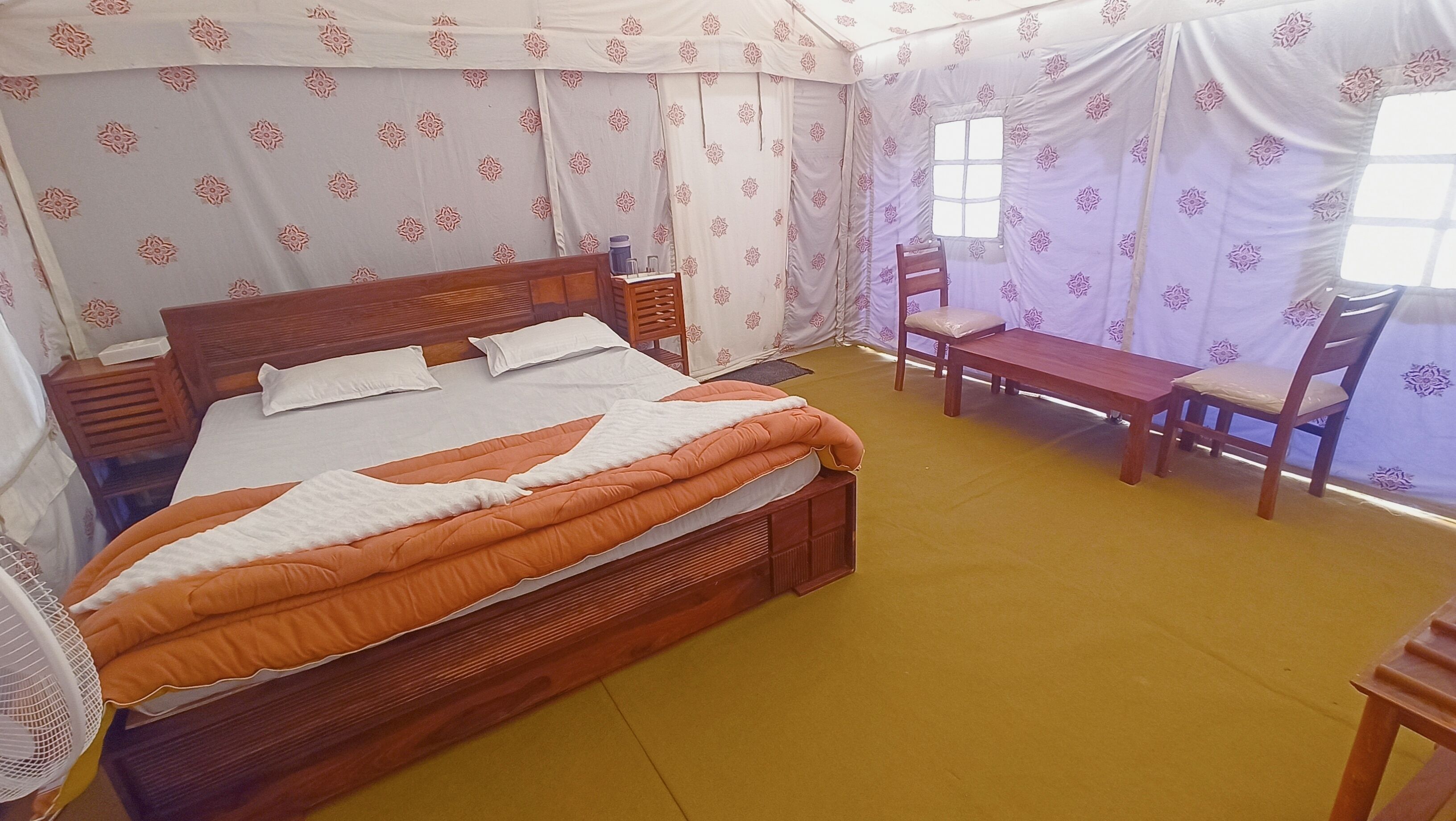 A single bedroom with a bed, bedside tables, a bench, and chairs.