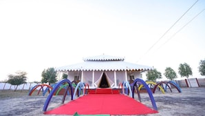 A white tent with a red carpet entrance, surrounded by colorful arches.