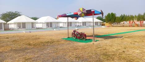 A tented area with a motorcycle parked under a colorful umbrella.