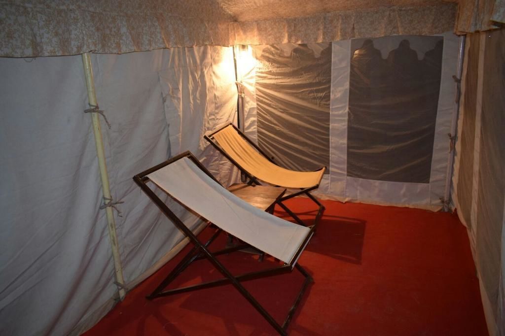 Una carpa con una sola silla reclinable y un piso cubierto de alfombra roja.