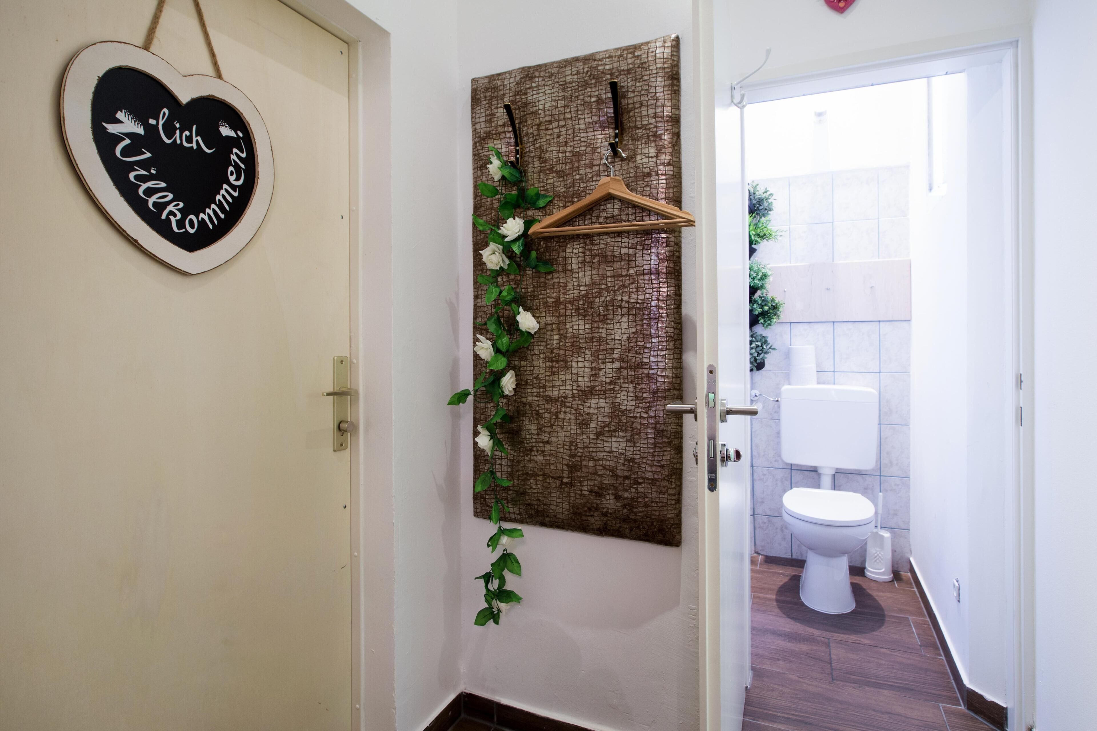 Een badkamer met een hartvormig bord, een houten kleerhanger en een spiegel met een reliëfachtergrond.