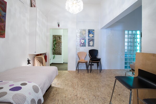 A bedroom with a bed, a desk, two chairs, and a door leading to another room. - Apartment suite, downtown, near Hundertwasserhaus 2 rooms (Wien)