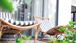 Un espace patio aménagé avec des fauteuils de jardin en osier et un sol à carreaux.
