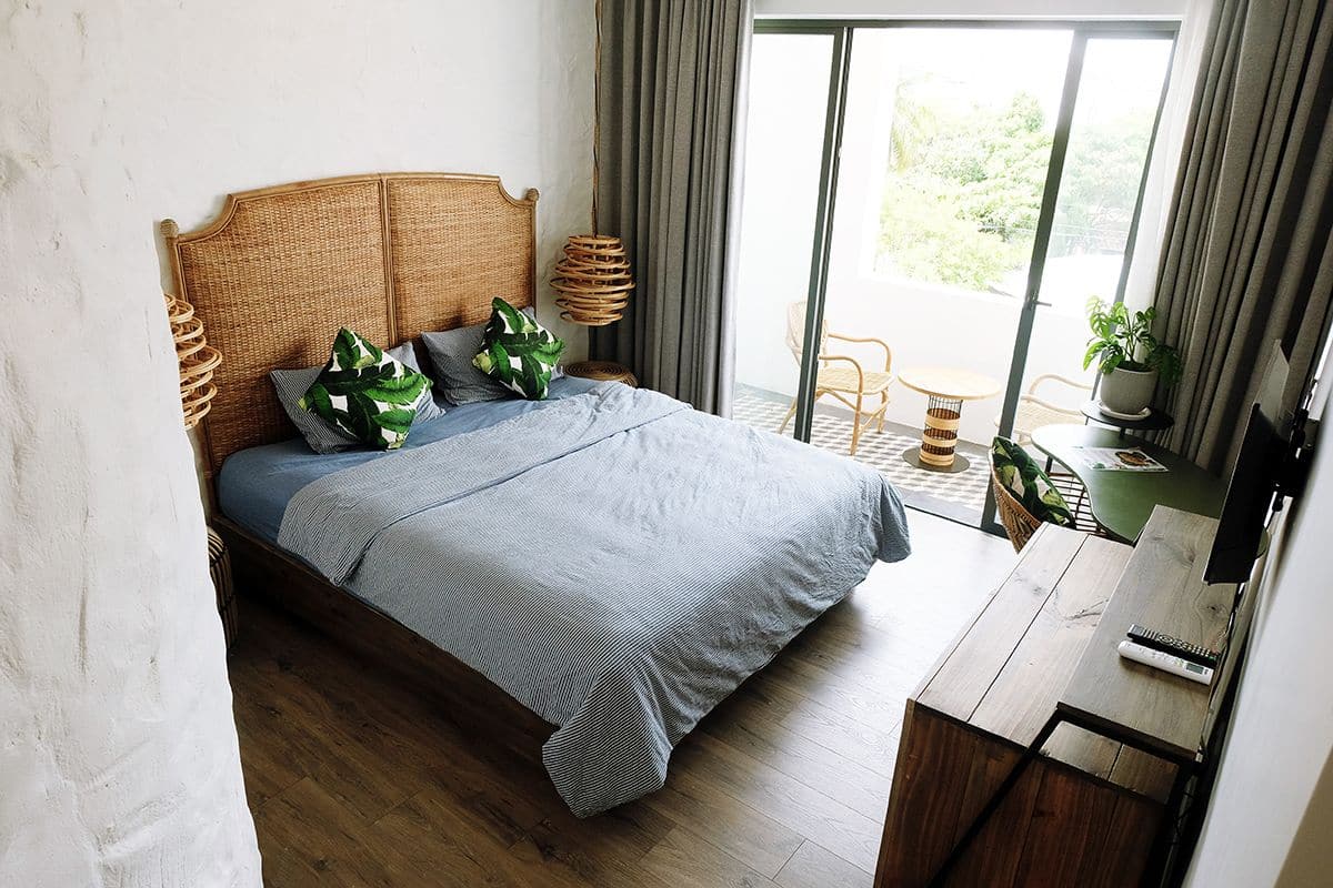 A bedroom with a bed, a desk, and a view of the outdoors.