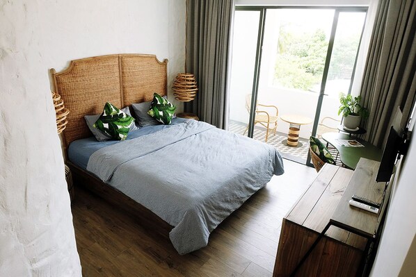 A bedroom with a bed, a desk, and a view of the outdoors.