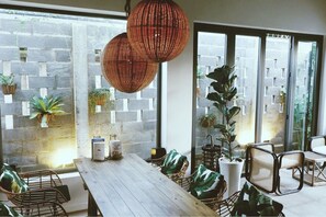 A dining area with a wooden table, wicker chairs, and hanging wicker lamps.