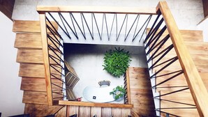 Un escalier en bois avec une rampe en métal, un skateboard et une plante en pot.
