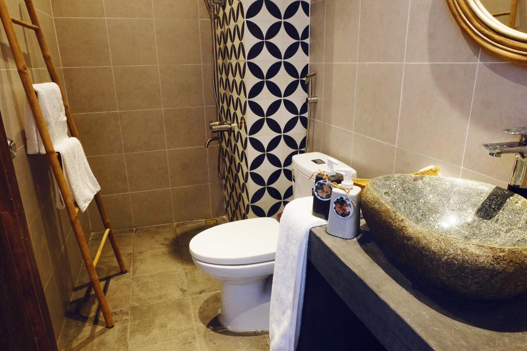 A bathroom with a toilet, a shower, a stone sink, and a towel rack.