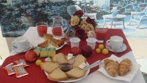 Una mesa de desayuno con diversos alimentos, como pan, pasteles, frutas y bebidas.