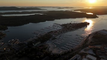 Vista aérea de un puerto deportivo con barcos amarrados, rodeado de agua y tierra.