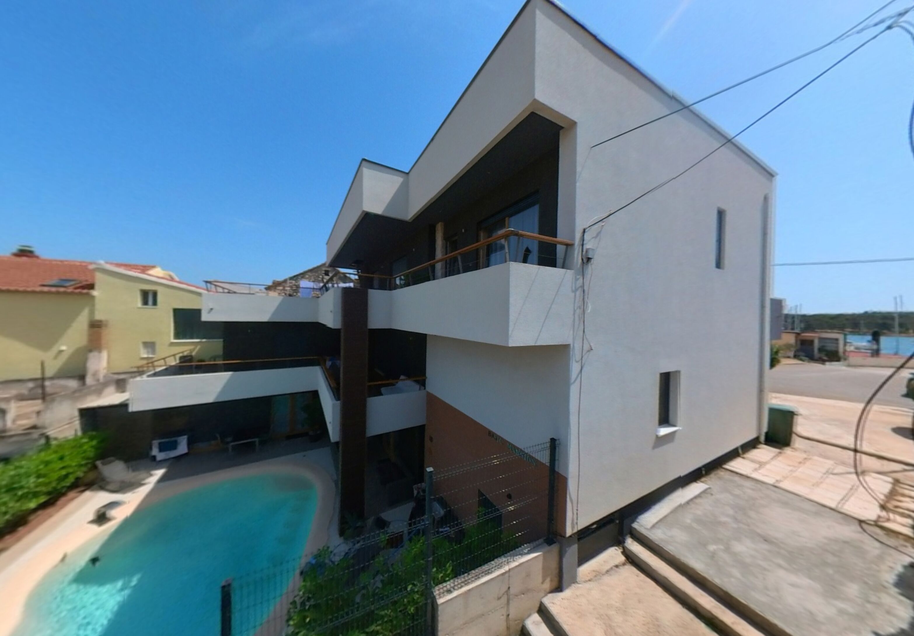 Un bâtiment moderne à deux étages doté d’une piscine, de balcons et d’un toit plat.