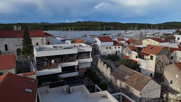 Un pueblo costero con edificios tradicionales, un puerto deportivo con veleros y vistas al mar.