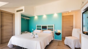 Une chambre moderne avec un grand lit, une table de chevet, une chaise et un mur d’accent de couleur turquoise.