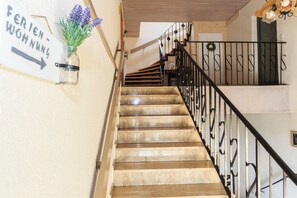 A staircase with a sign indicating directions to the living room and a small vase with flowers on the wall.