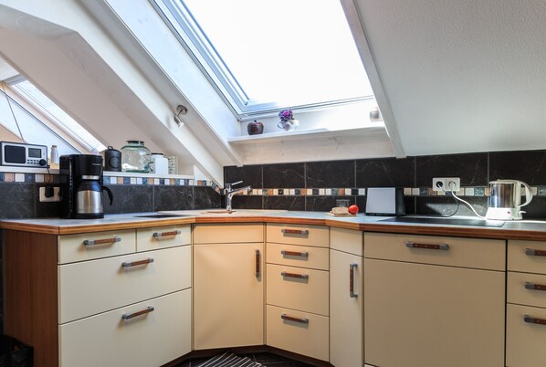 A kitchen with a skylight, a coffee maker, a toaster, and a kettle.