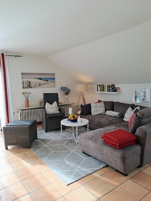 A living room with a sofa, armchair, coffee table, and a radiator. - Apartment Bergblick - Countryside View (Hergatz)