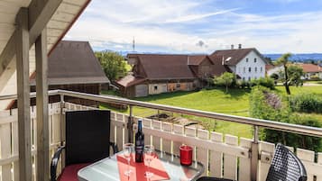 Ein Balkon mit Tisch, Stühlen und einer Weinflasche.