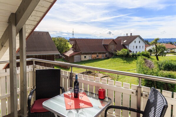 A balcony with a table, chairs, and a bottle of wine.