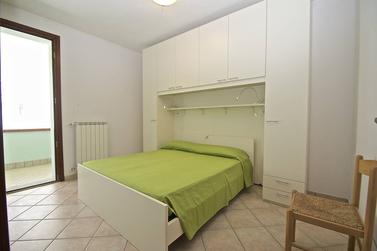 Ein Schlafzimmer mit Bett, einem Sessel, einem Kleiderschrank und einer Heizung.