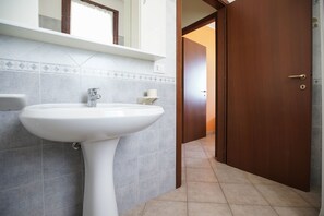 A bathroom with a white sink, a mirror above it, and a door leading to another room. - Residence Smith Fronte Mare (Comacchio)