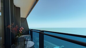 Ein Balkon mit einem Glastisch, Stühlen und einem Blumenstrauß.