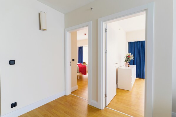 A hallway with a bed, a desk, and a blue curtain in the background.