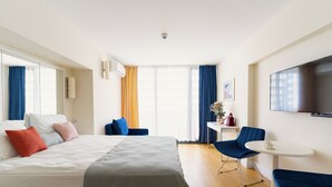 Ein Hotelzimmer mit Bett, Fernseher, Schreibtisch und Stuhl.
