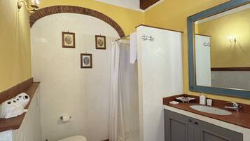 A bathroom with a toilet, shower, and sink.