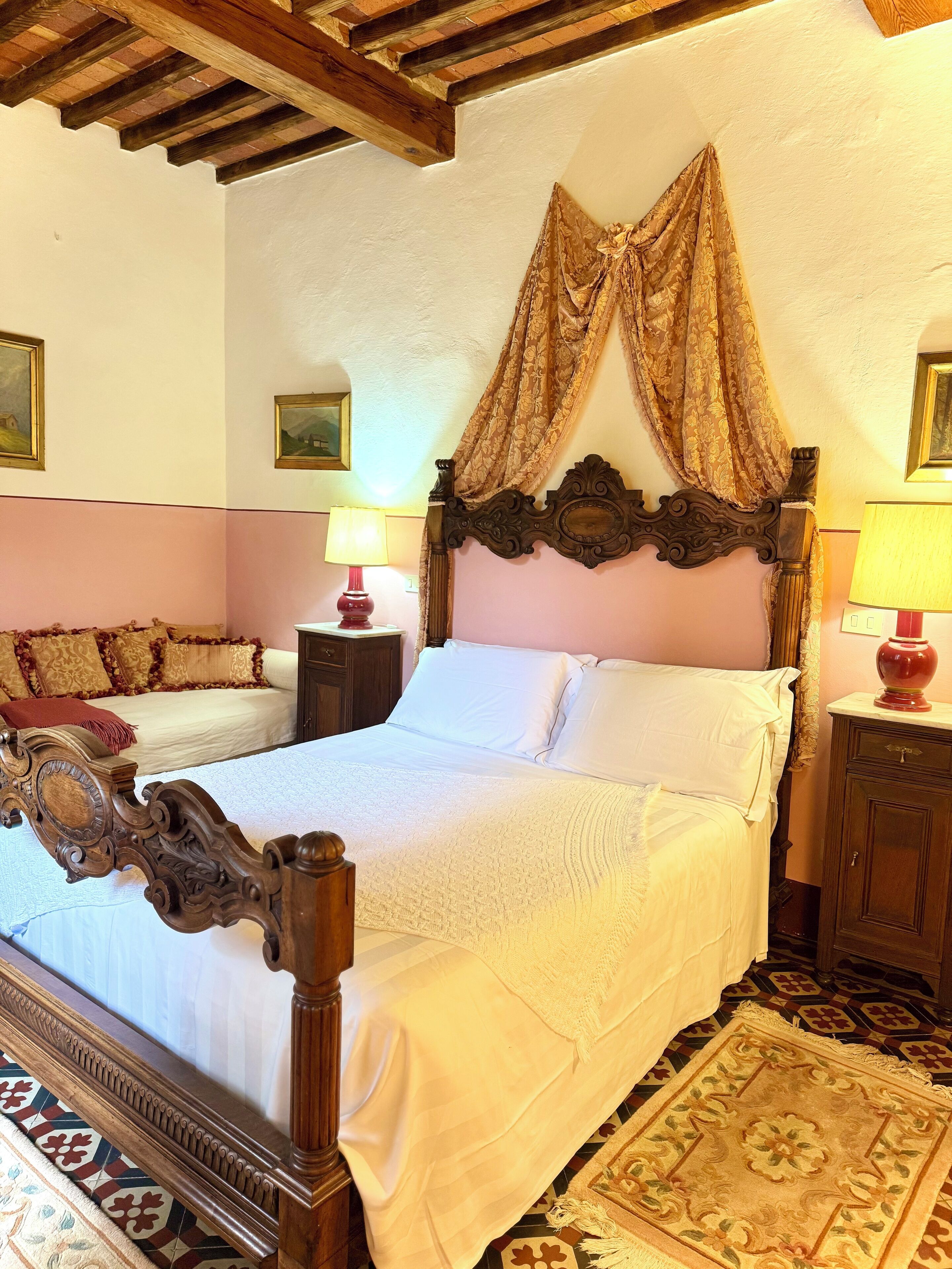 A traditional bedroom with a four-poster bed, a patterned rug, and a wooden ceiling.
