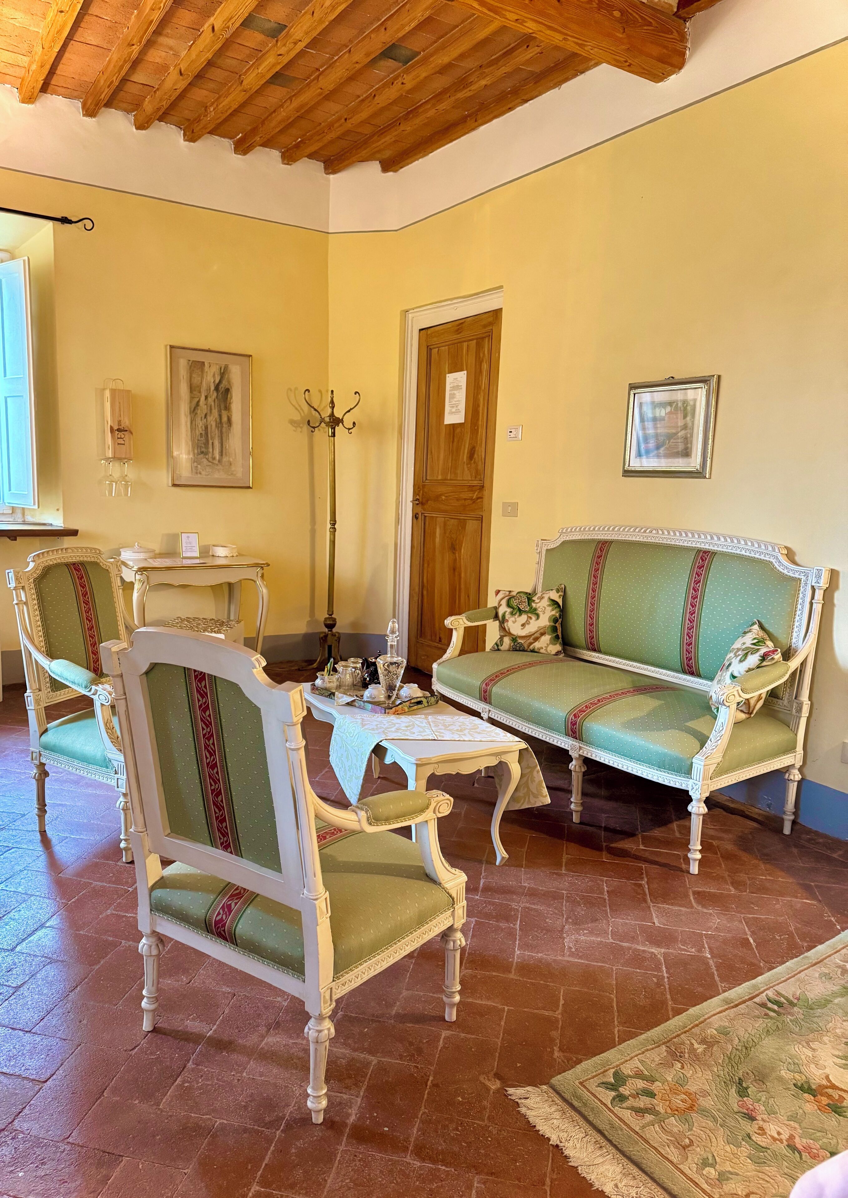 Une pièce avec un plafond en bois, un canapé vert, deux fauteuils, une petite table et un tapis.