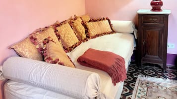 A bedroom with a bed, pillows, a lamp, and two paintings on the wall.