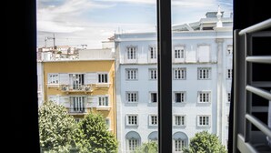 Vista de un edificio con múltiples ventanas y balcones, visible a través de un marco de ventana.