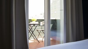 Habitación de hotel con puerta corrediza de vidrio que da a un área exterior con mesa y sillas.